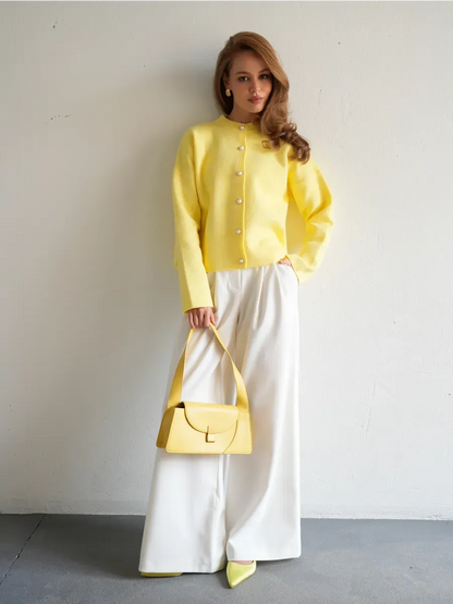 Lemonade Cardigan by Lauven in vibrant yellow, paired with white wide-leg trousers and a matching handbag.