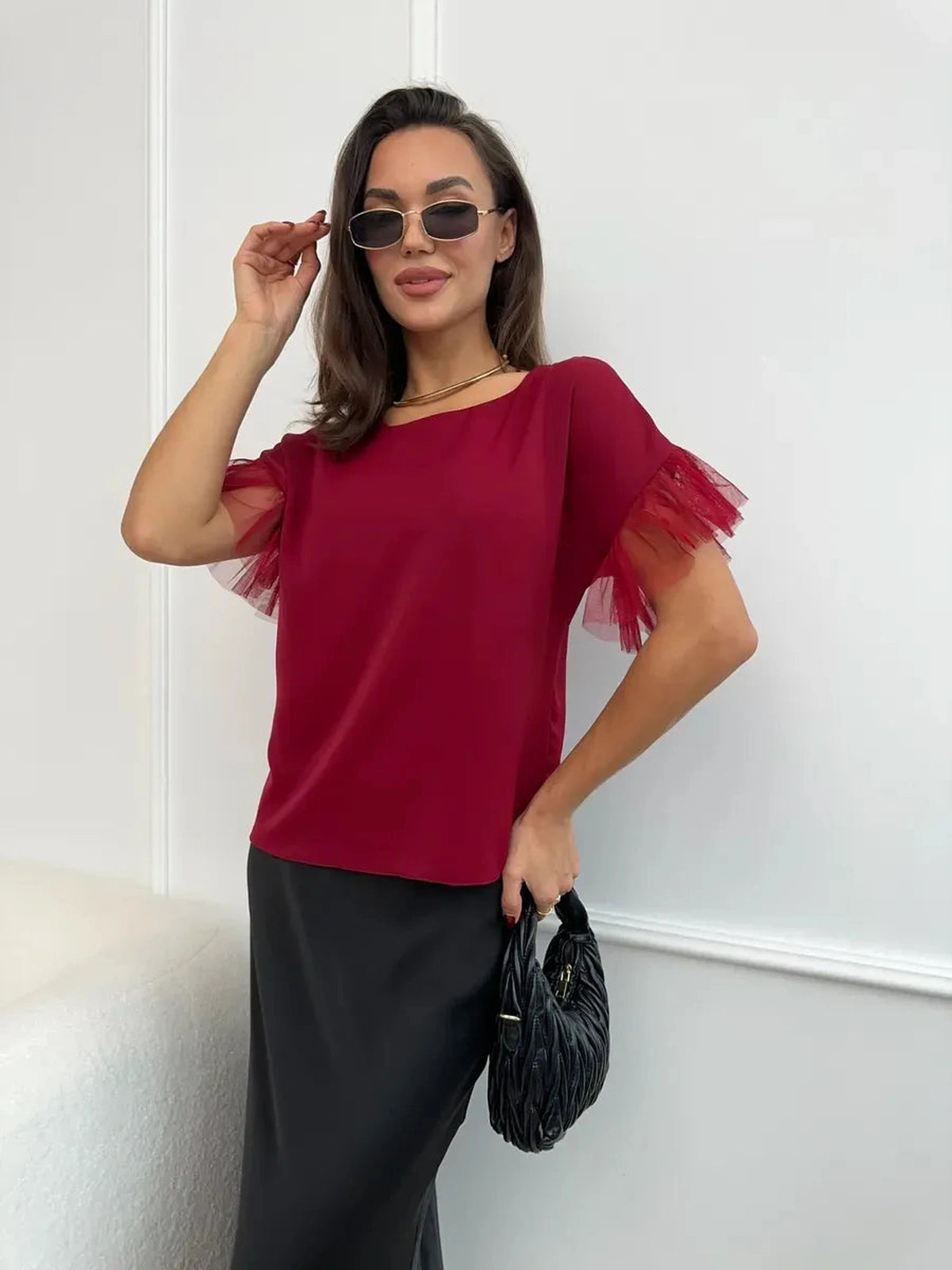 Velora Blouse by Lauven in burgundy featuring sheer ruffle sleeves, styled with sunglasses and a black handbag.