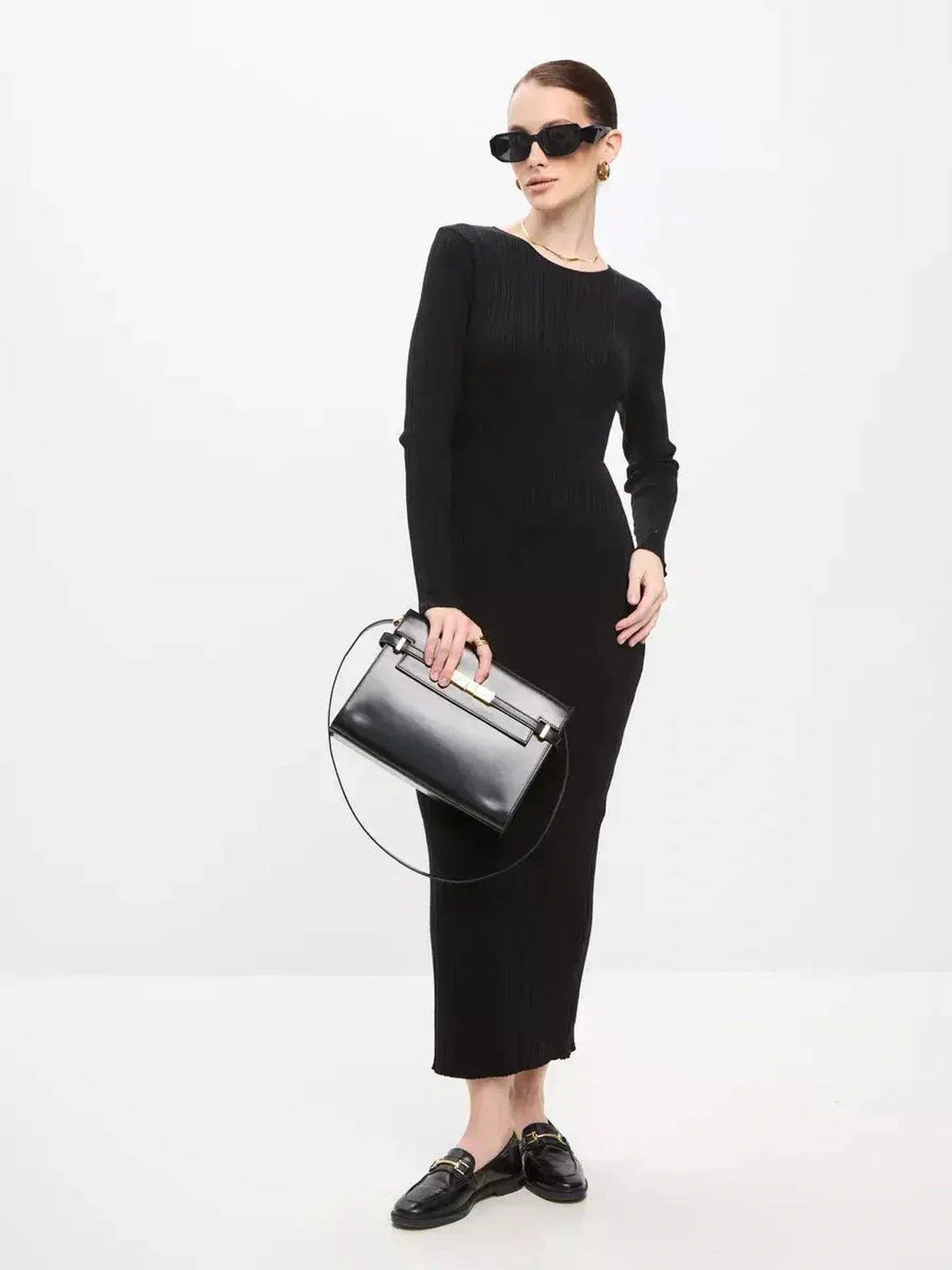 Model showcasing a Sculpted Rib Maxi Dress with long sleeves, paired with a sleek black handbag and modern sunglasses.