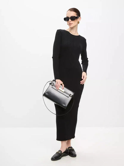 Model showcasing a Sculpted Rib Maxi Dress with long sleeves, paired with a sleek black handbag and modern sunglasses.