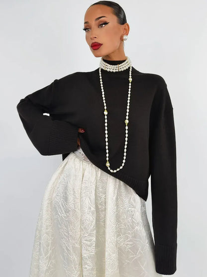 Model showcasing the Noir Sweater by Lauven, an oversized black knit paired with a stylish skirt.