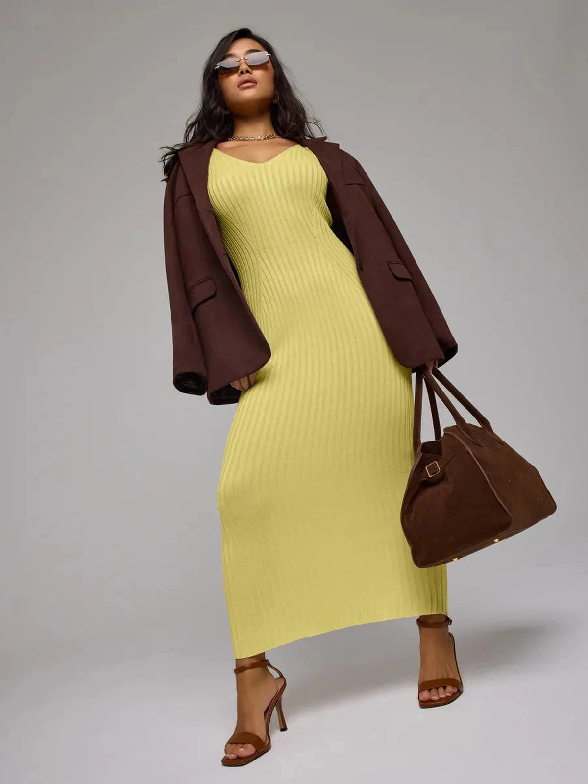 Elegant model wearing Soleil Maxi Dress in vibrant yellow, styled with a brown blazer and handbag, showcasing Lauven brand.