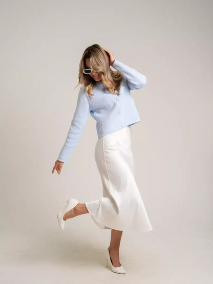 Model showcasing Celeste Cardigan by Lauven in light blue, paired with a white skirt and stylish heels.