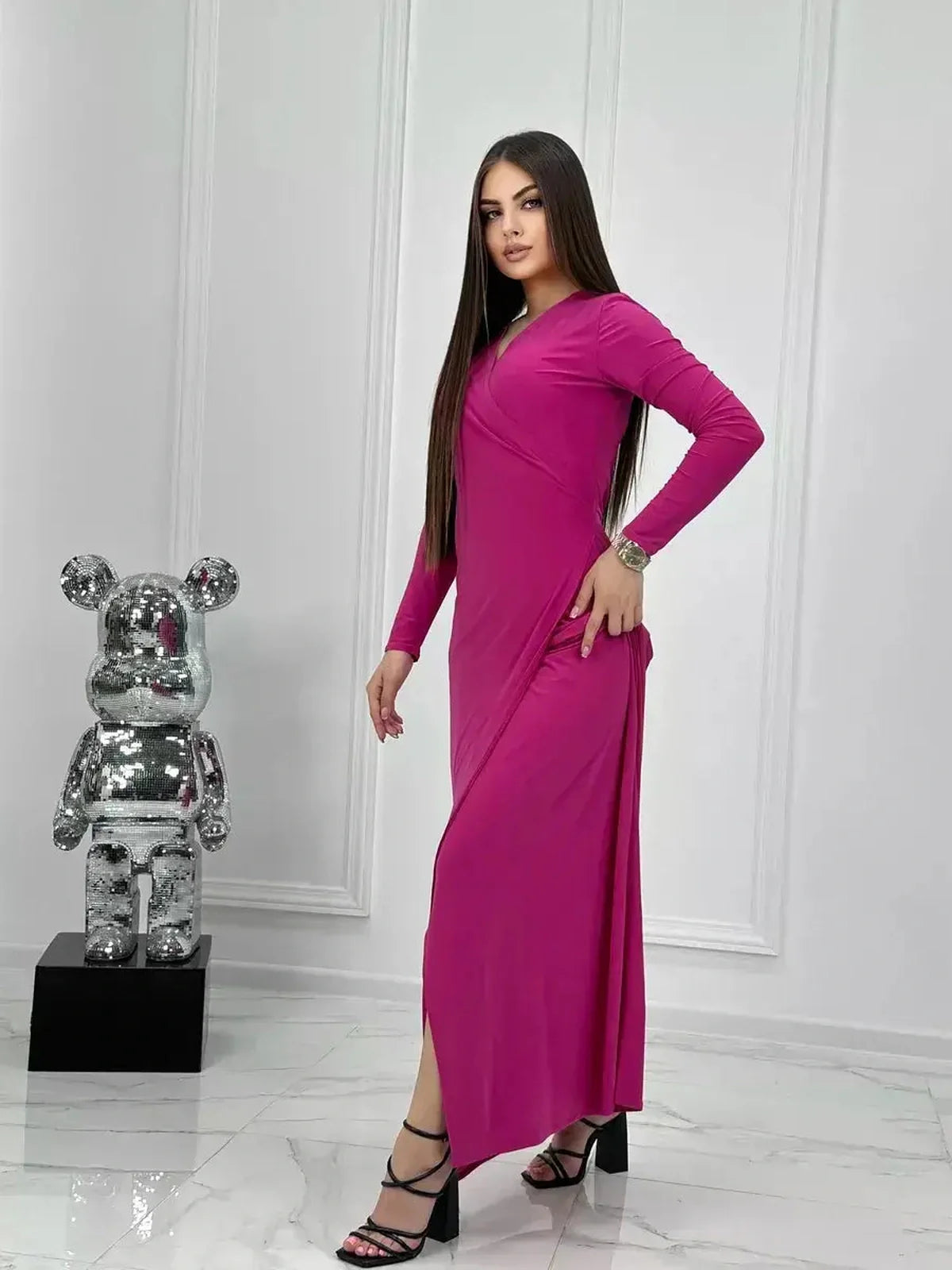 Model in a pink Velora Maxi Dress with long sleeves and side slit, showcasing elegance and glamour.