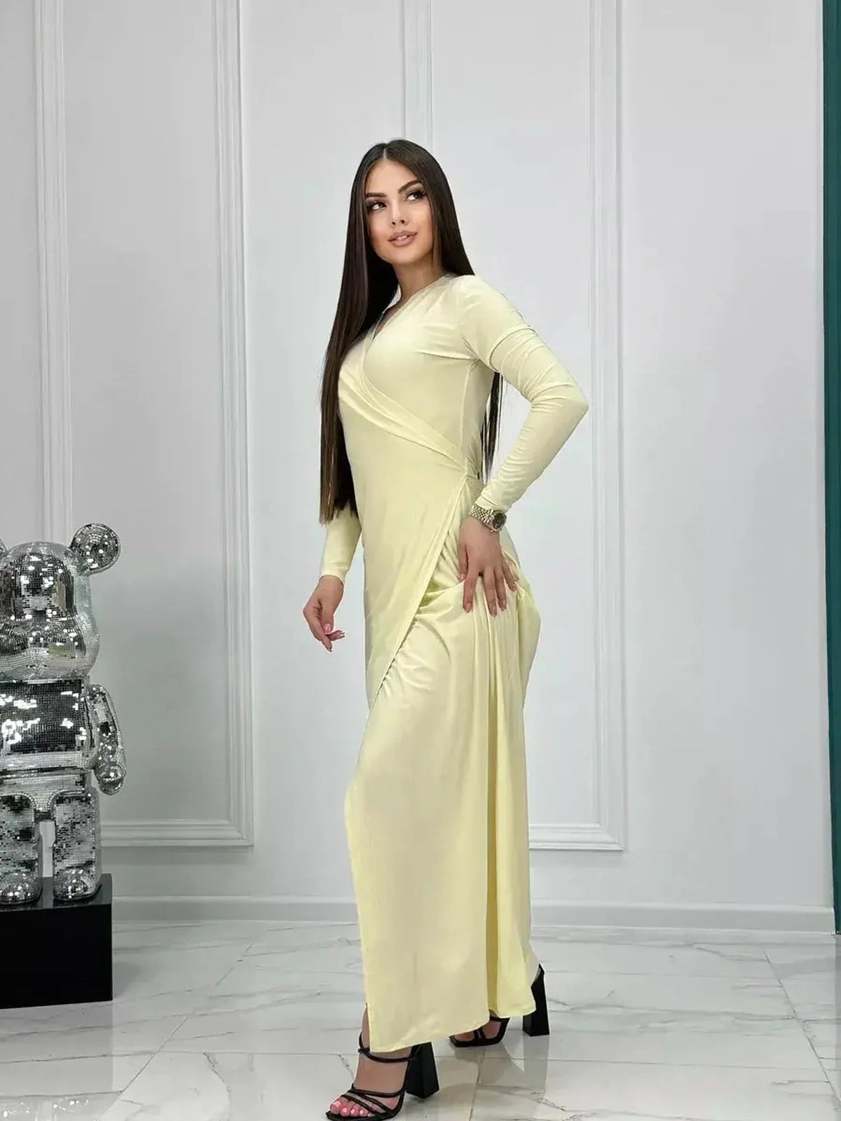 Model showcasing the Celeste Wrap Maxi Dress in luminous buttercream, featuring sleek draping and elegant silhouette.