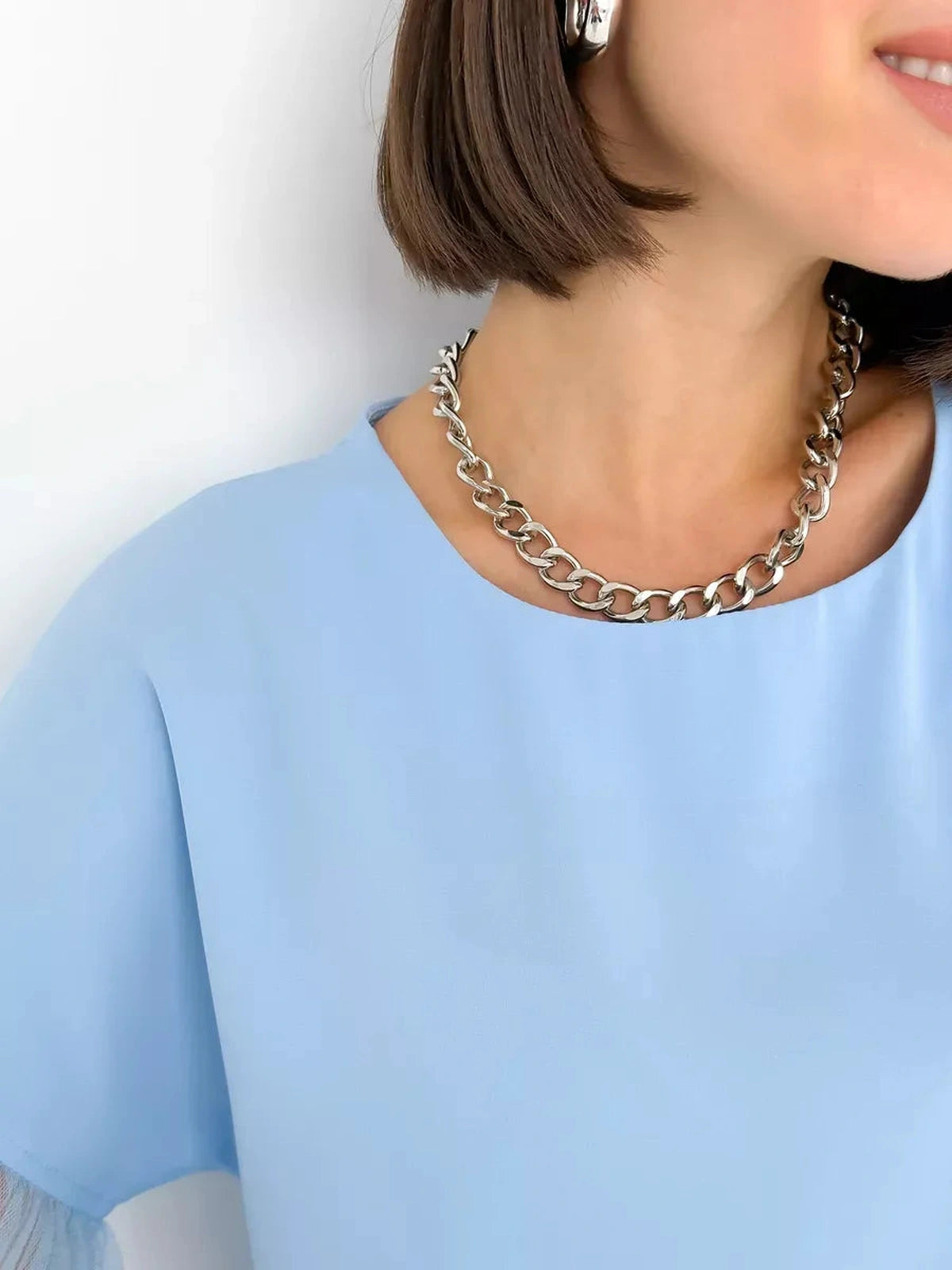 Celeste Blouse by Lauven, featuring a light blue silk-like top with tulle details and a stylish silver chain necklace.
