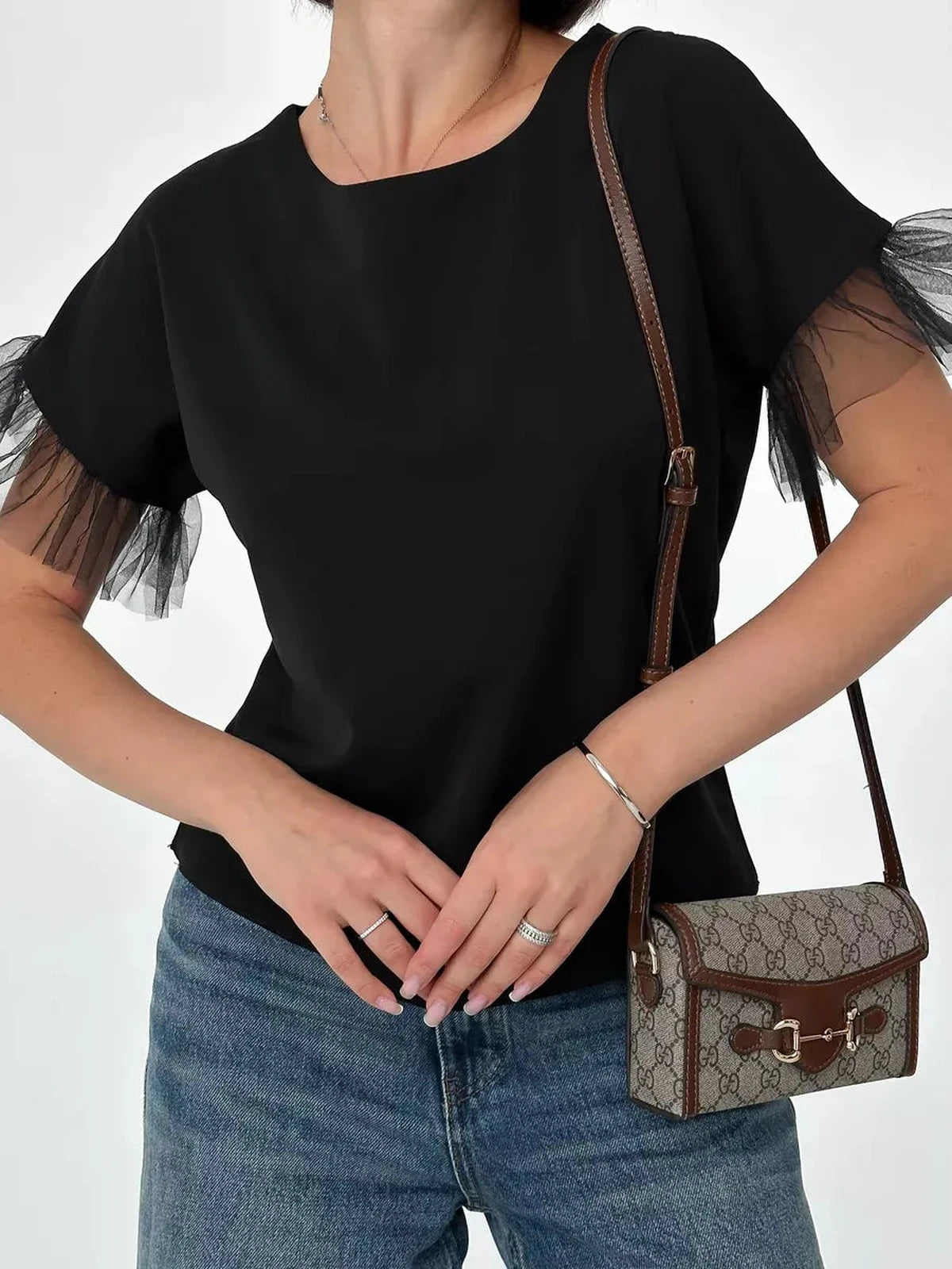 Noiré Blouse by Lauven, elegant short sleeve black blouse with tulle ruffle detail, styled with a chic handbag.