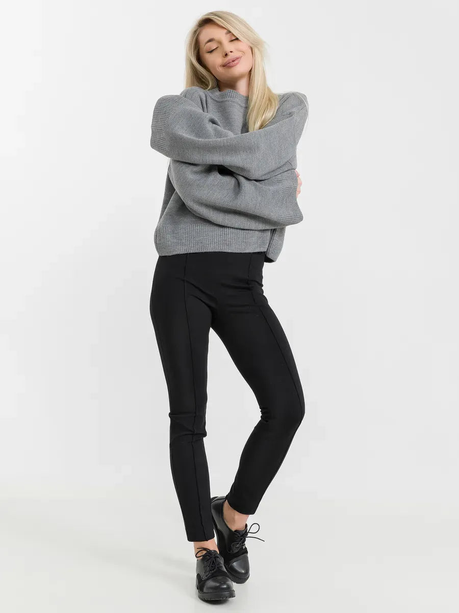 Model wearing the Astra Sweater by Lauven in grey knitwear, paired with black pants for a trendy casual look.