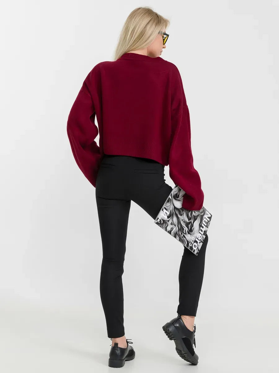 Back view of a woman wearing a burgundy Marbella Sweater by Lauven, styled with black pants and a chic clutch.