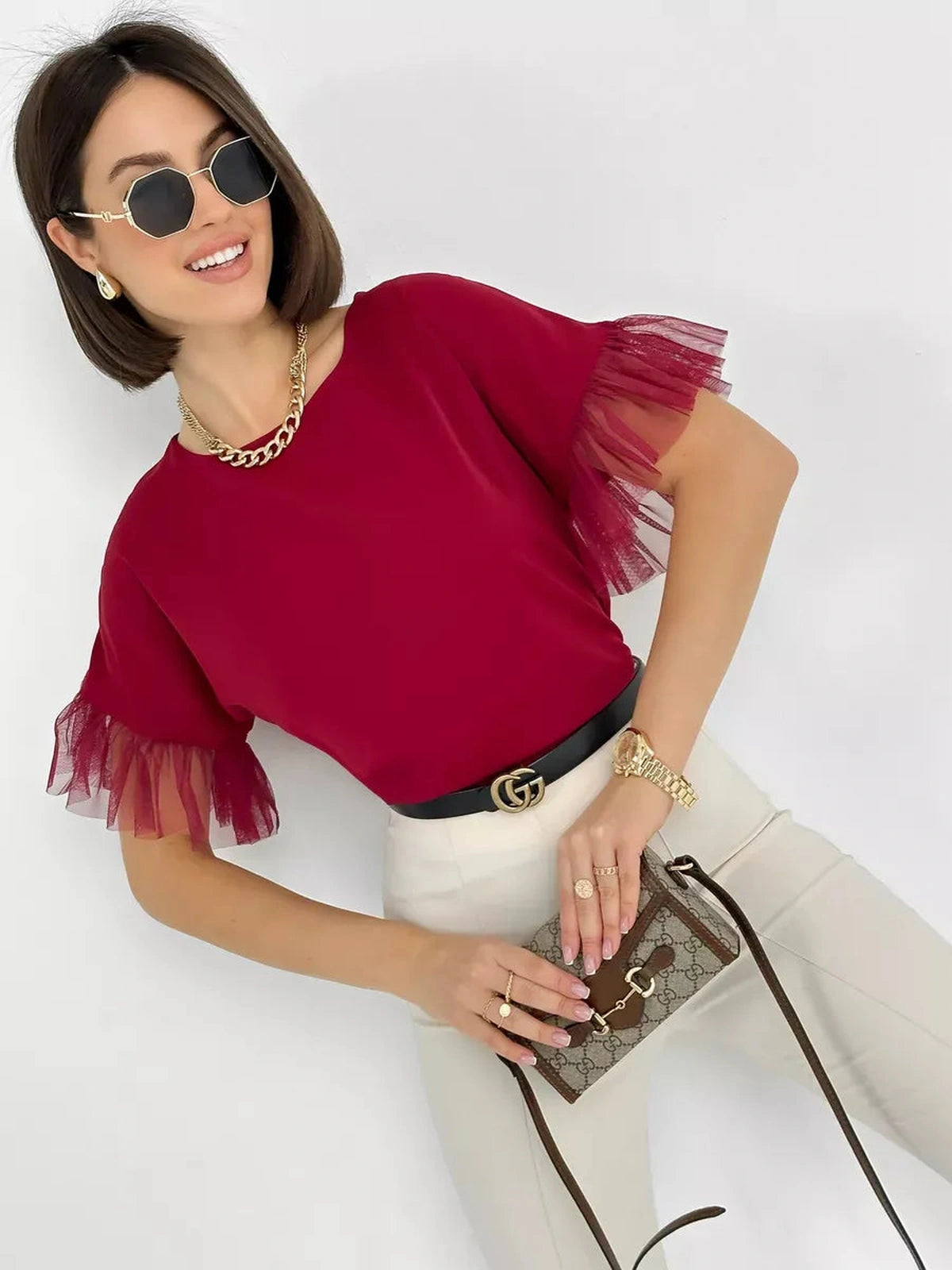 Model wearing Velora Blouse by Lauven, a burgundy blouse with sheer ruffle sleeves and stylish accessories.