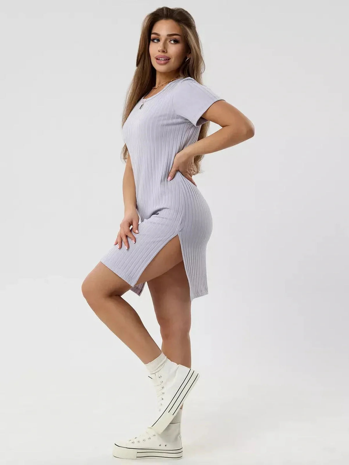 Model wearing a light purple ribbed summer mini dress with short sleeves and side slit, paired with stylish white boots.