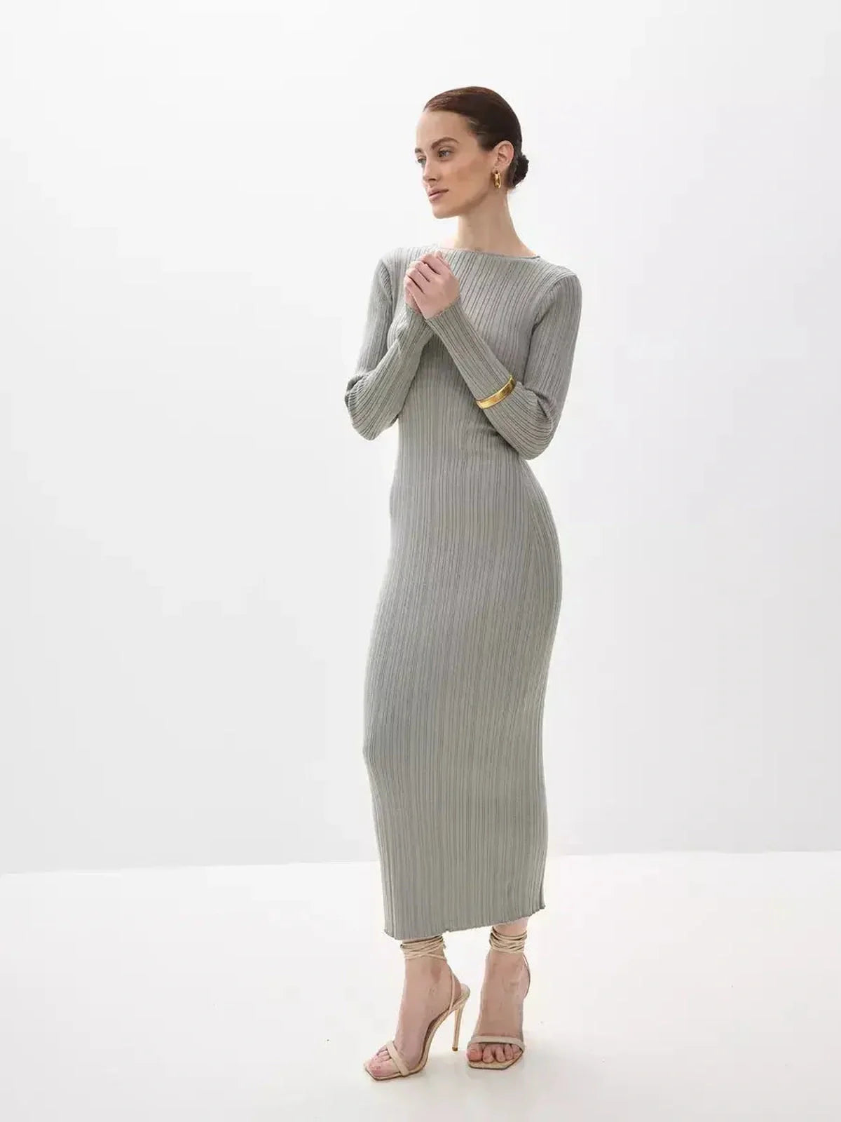 Model wearing the Sculpted Grace Maxi Dress, a fitted ribbed knit gown in soft gray, showcasing elegance and comfort.
