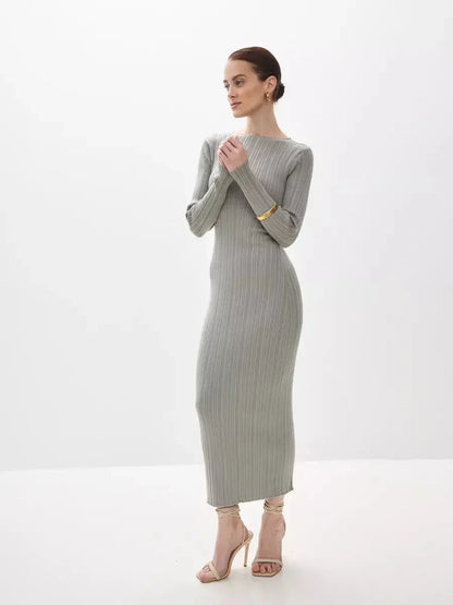 Model wearing the Sculpted Grace Maxi Dress, a fitted ribbed knit gown in soft gray, showcasing elegance and comfort.
