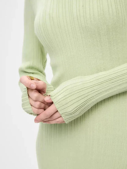 Close-up of hands in ribbed long sleeves of a light green Celery Luxe Maxi Dress, showcasing soft and elegant fabric.