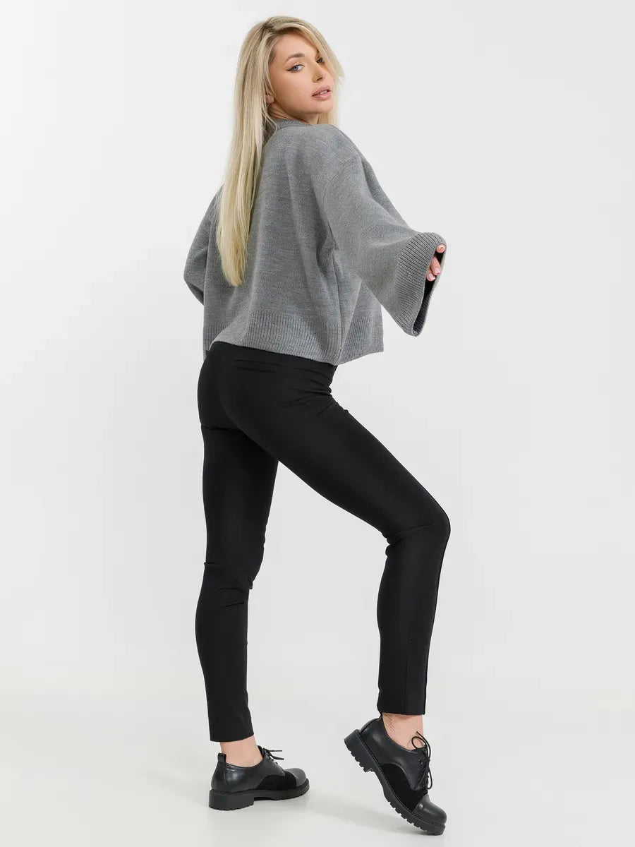 A woman wearing the Astra Sweater in grey, styled with black leggings for a modern look by Lauven.