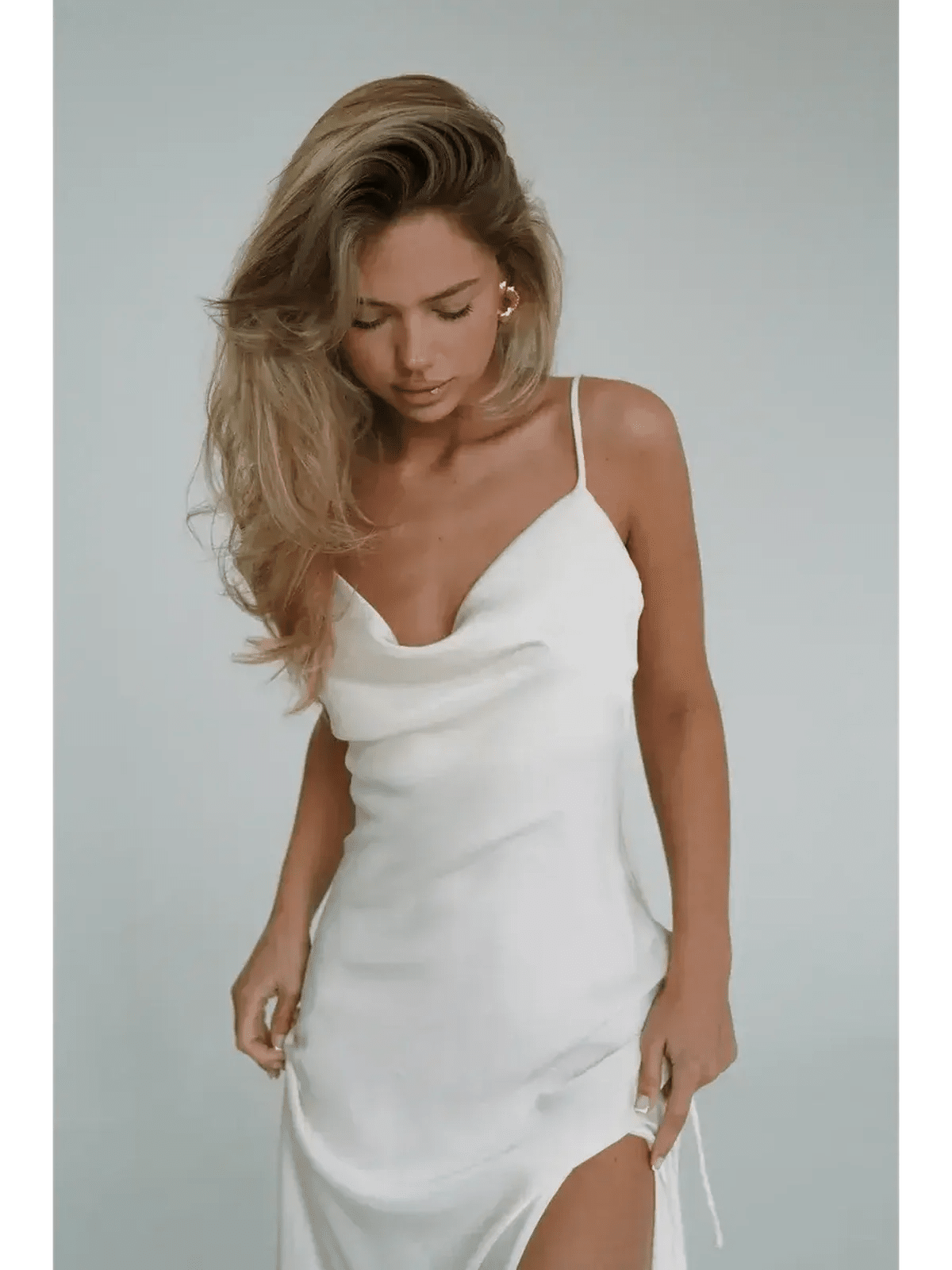 Elegant woman in Ivory Luxe Maxi Dress featuring silky drape, cowl neckline, and high side slit.