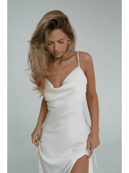 Elegant woman in Ivory Luxe Maxi Dress featuring silky drape, cowl neckline, and high side slit.