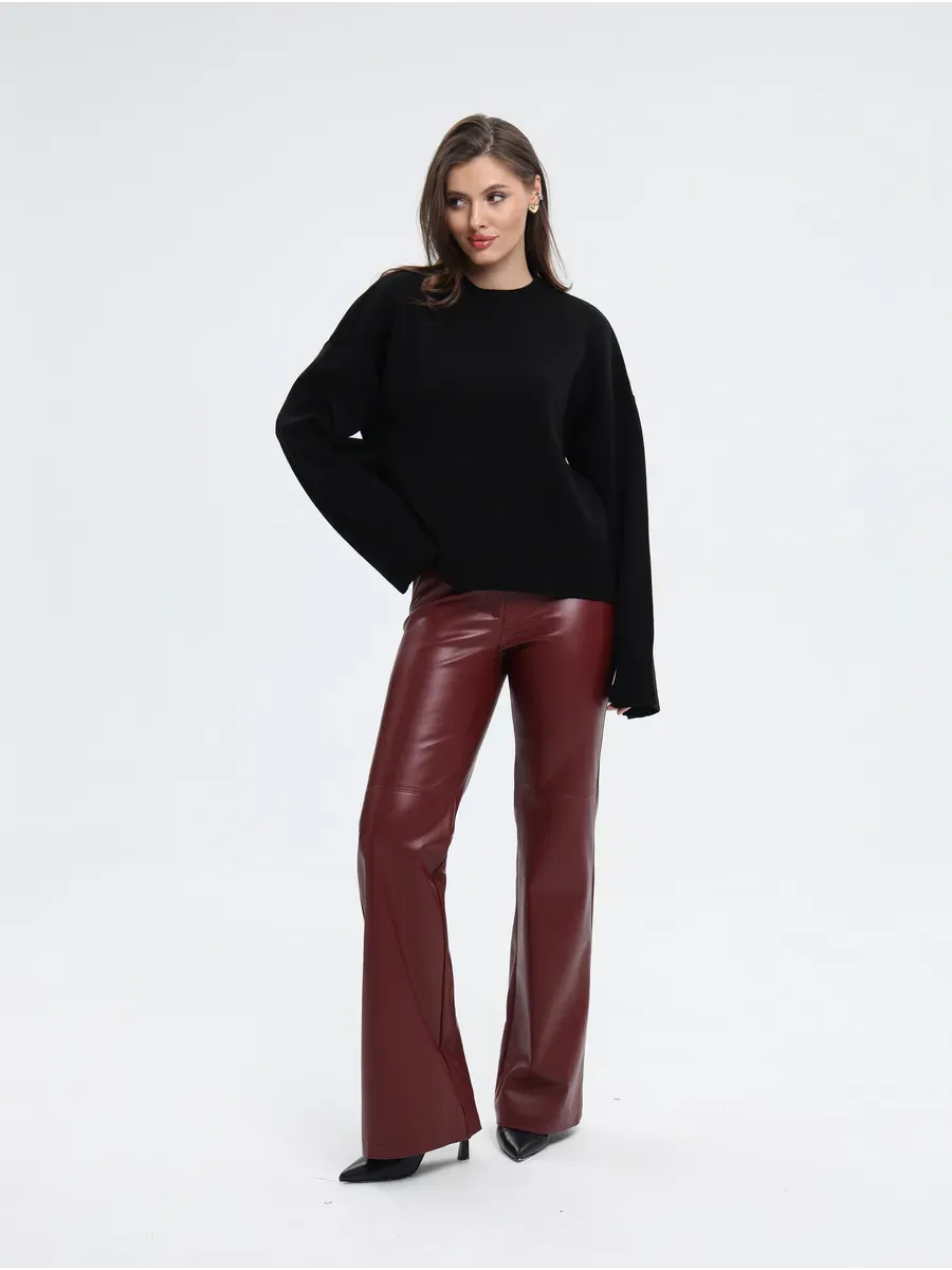 Model wearing the Lauven Seren Sweater in black, styled with burgundy leather pants for a chic look.