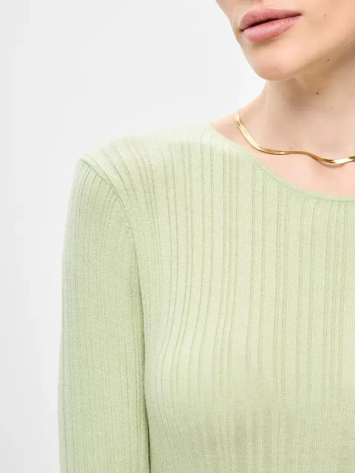 Close-up of a light green ribbed dress showcasing a seamless fit and elegant neckline.