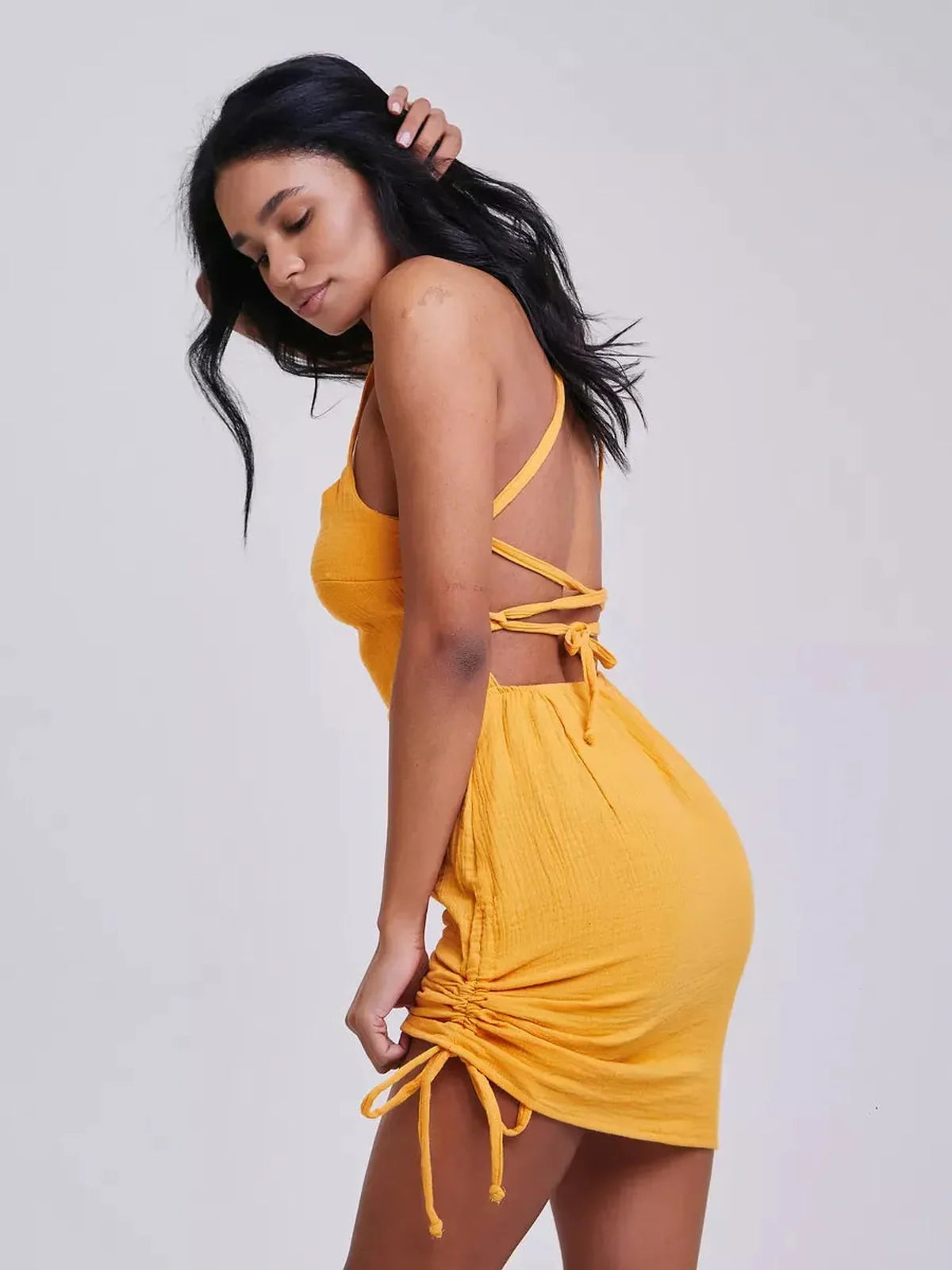 Model showcasing the Citrus Rush mini dress in vibrant yellow, featuring adjustable crisscross straps and a bodycon silhouette.