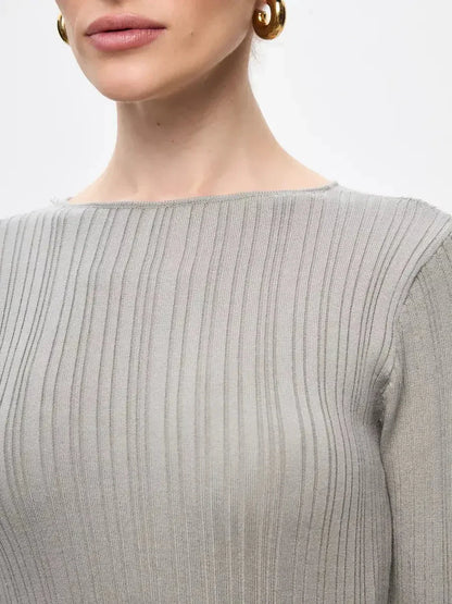 Close-up of a woman wearing a soft ribbed knit maxi dress showcasing its sculpted fit and elegant neckline.