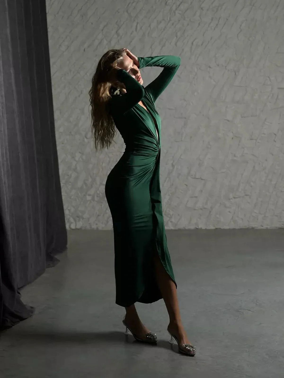 Model in a deep emerald Sculpted Drape Maxi Dress showcasing dramatic draping and a plunging neckline.