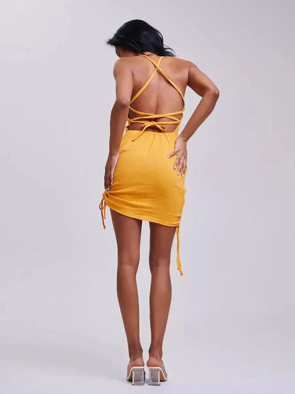 Back view of a woman in a yellow bodycon mini dress with adjustable crisscross straps for summer styling.