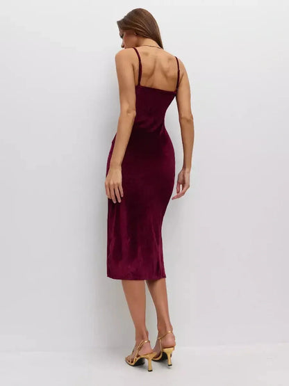 Back view of a woman in a burgundy midi dress made of plush velvet, featuring thin straps and an elegant silhouette.