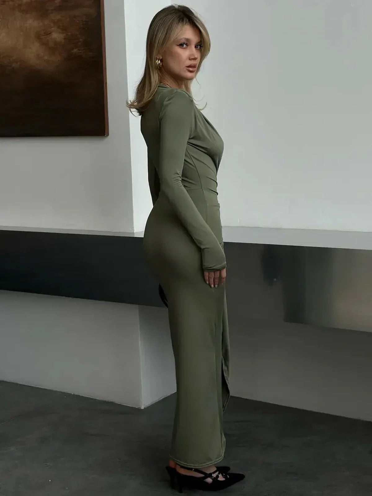 Model wearing a Sculpted Drape Maxi Dress in light sage, showcasing a deep V neckline and elegant silhouette.