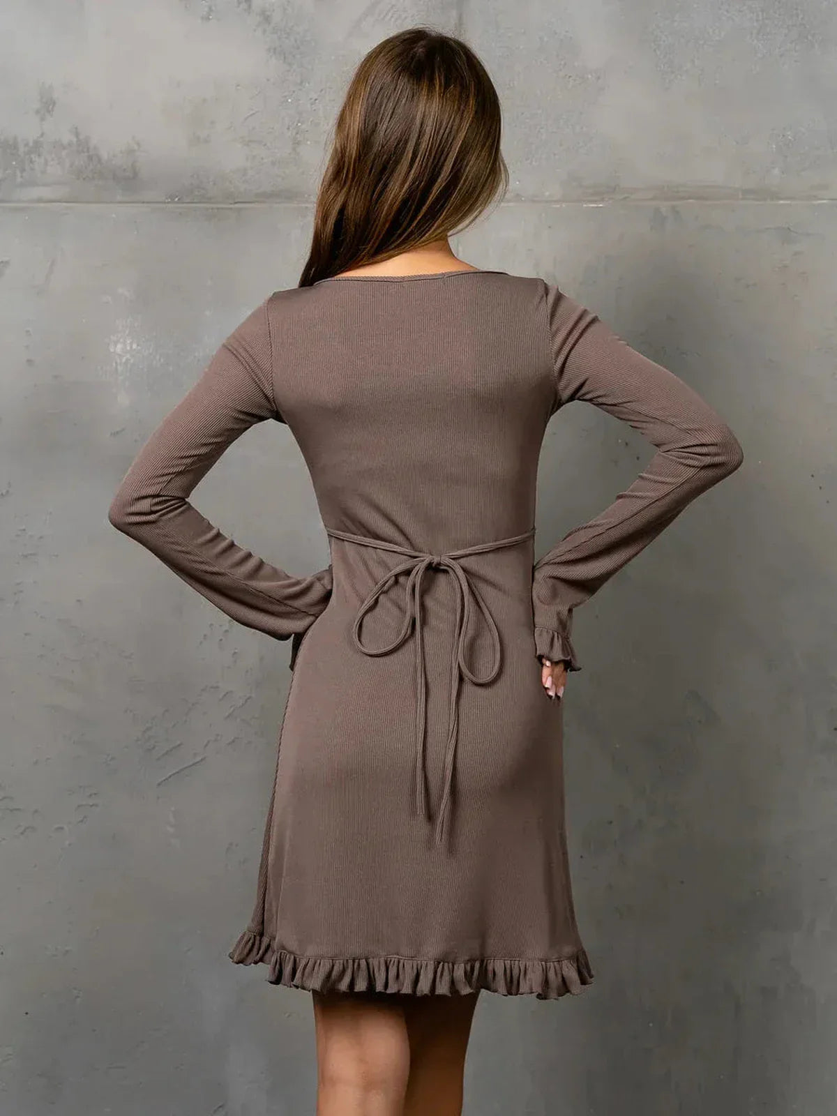 Back view of Cocoa Flare long sleeve dress in cocoa brown with ruffle trim and adjustable tie waist.