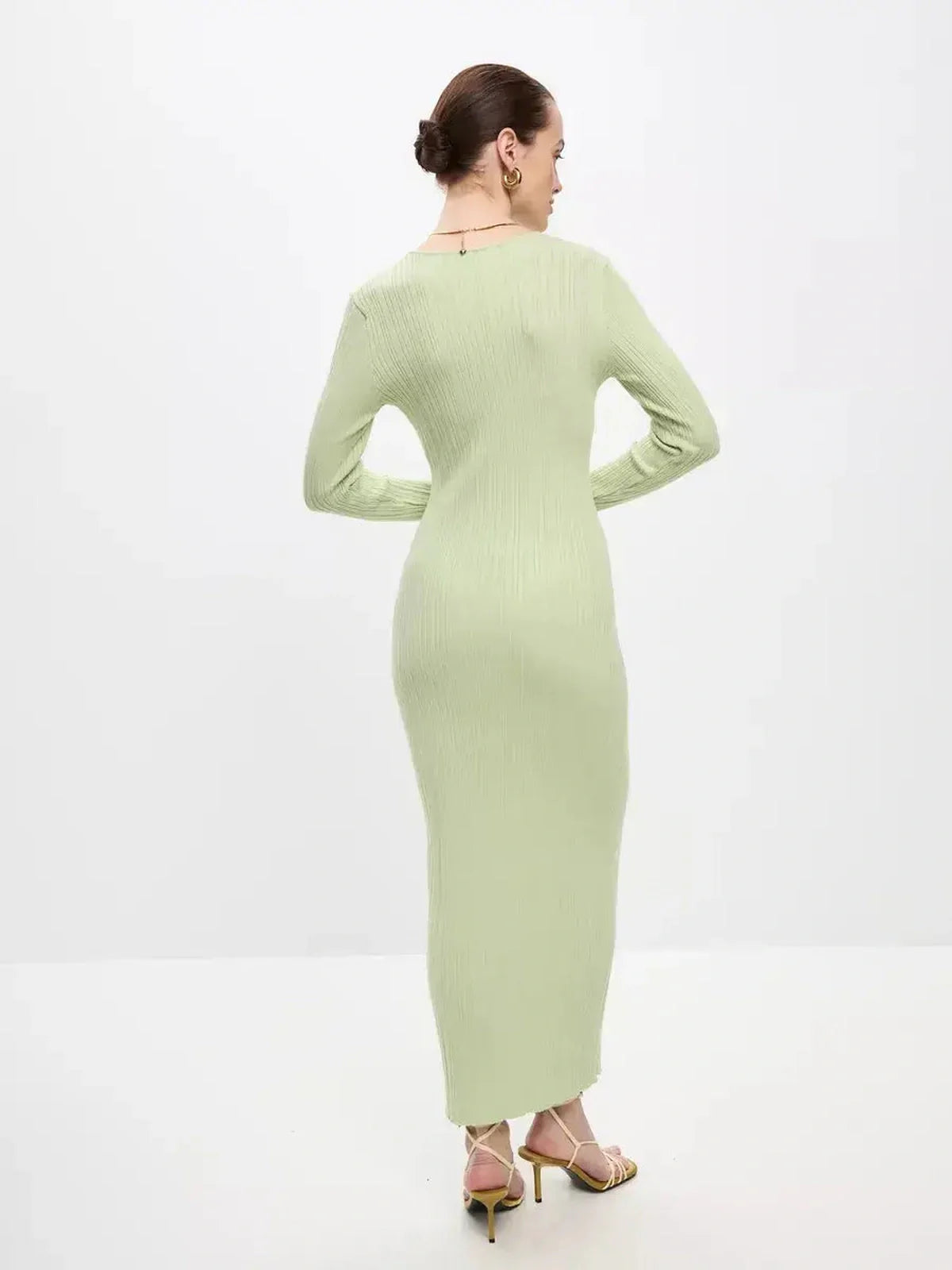 Back view of a woman in a light green Celery Luxe Maxi Dress, showcasing its ribbed knit and seamless silhouette.