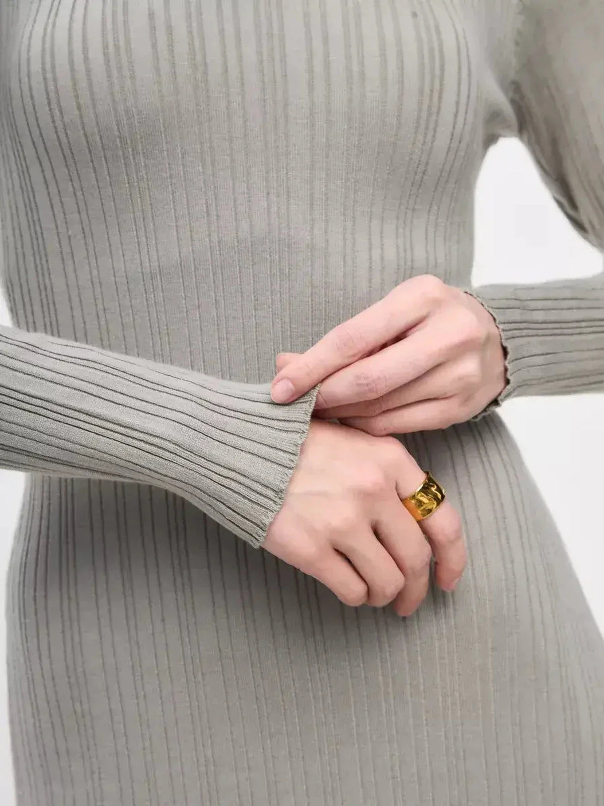 Close-up of hands adjusting the ribbed sleeve of the Sculpted Grace Maxi Dress in soft grey, showcasing sleek elegance and comfort.