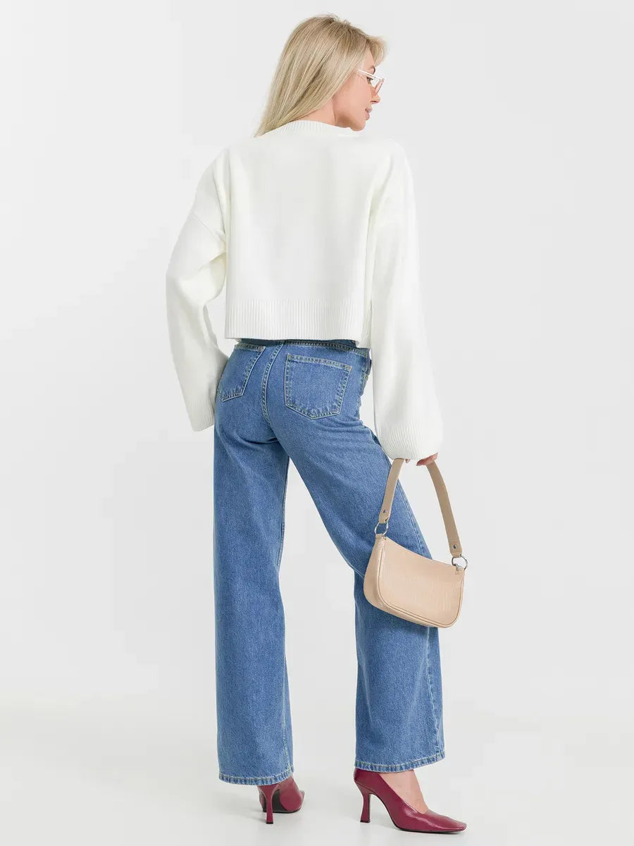 Woman wearing a Luna Sweater in ivory with denim jeans and a handbag, showcasing timeless versatility by Lauven.