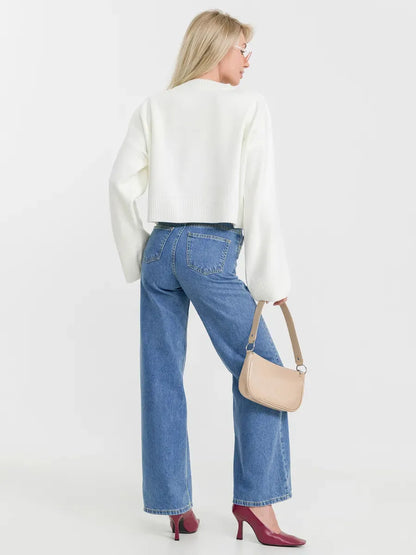Woman wearing a Luna Sweater in ivory with denim jeans and a handbag, showcasing timeless versatility by Lauven.