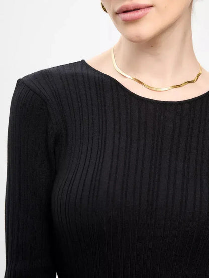 Close-up of a woman wearing a Sculpted Rib Maxi Dress in black with ribbed texture and a subtle gold necklace.