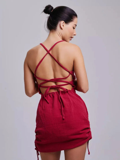 Back view of a woman wearing the Crimson Muse red dress, showcasing lace-up detail and fitted style.