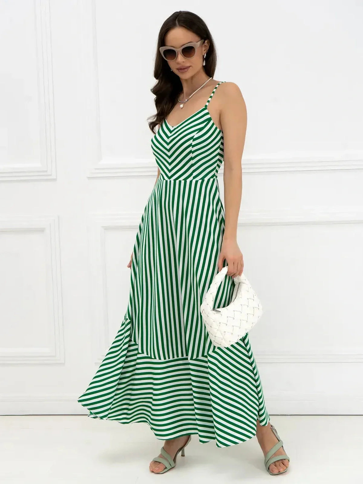 Model wearing the Verde Vibe Maxi Dress, featuring green and white stripes, U-neckline, and elegant bow-tie back.