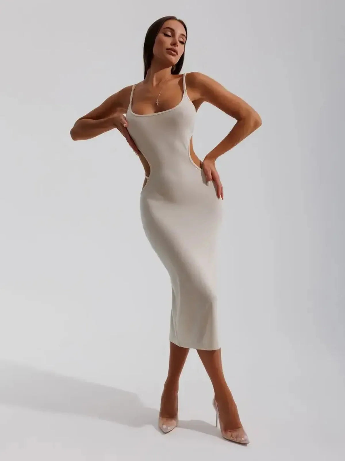 Elegant beige midi dress with sculpted side cutouts, showcasing a body-hugging silhouette and spaghetti straps.