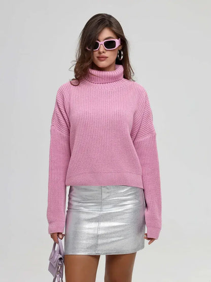 Iris Sweater by Lauven in pink, featuring an oversized fit and turtleneck, styled with a metallic skirt and sunglasses.