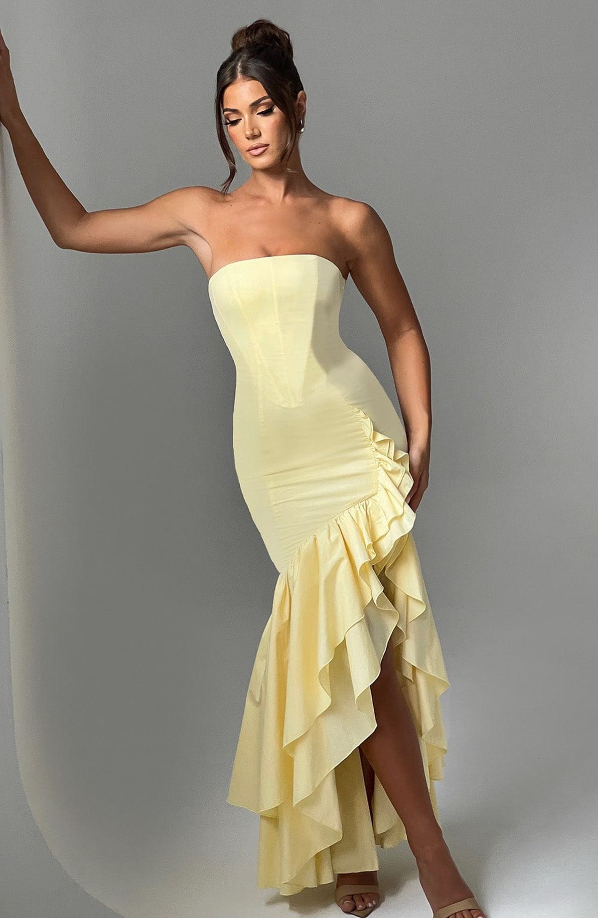 Strapless yellow gown with ruffles and high slit, perfect for summer weddings or evening events.