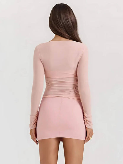 Rear view of the Juno Mini Dress in soft pink, showcasing its long sleeves and figure-hugging silhouette.