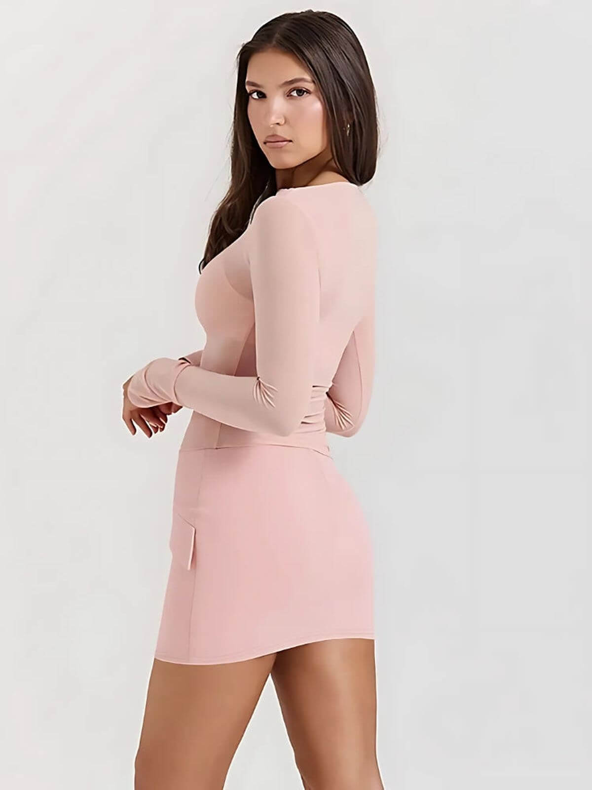 Model showcasing the Juno Mini Dress in soft pink, featuring long sleeves and a bodycon silhouette.