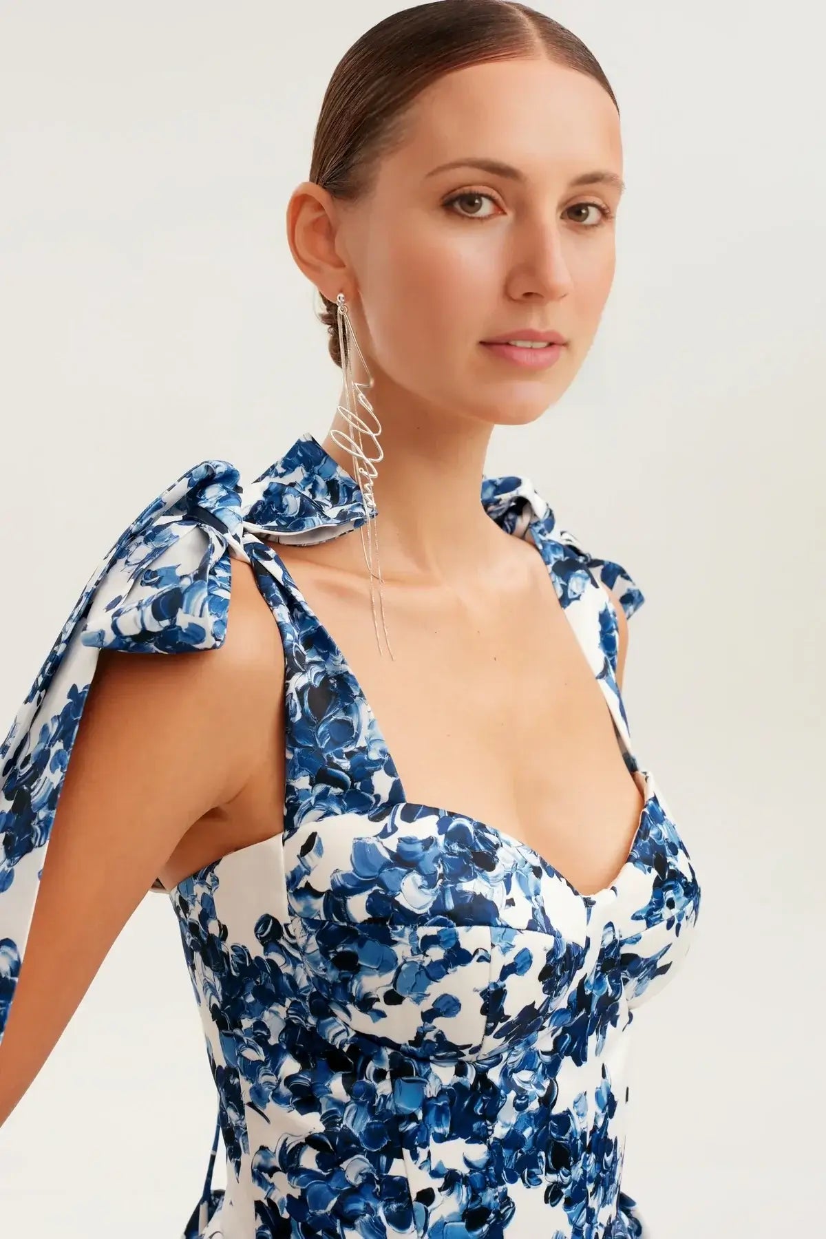 Elegant woman in a floral mini dress featuring a blue floral print and bow tie straps, perfect for summer occasions.