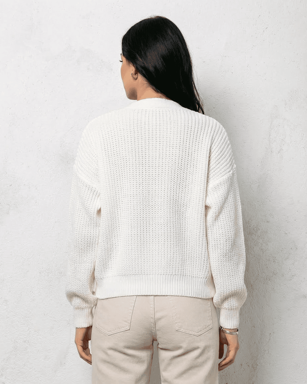 Back view of a woman wearing the Alba Cardigan by Lauven, showcasing its soft white knit design and relaxed fit.