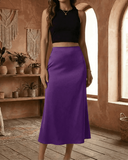 Model showcasing the Amethyst Midi Skirt by Lauven in vibrant purple satin, elegantly styled with a black crop top.