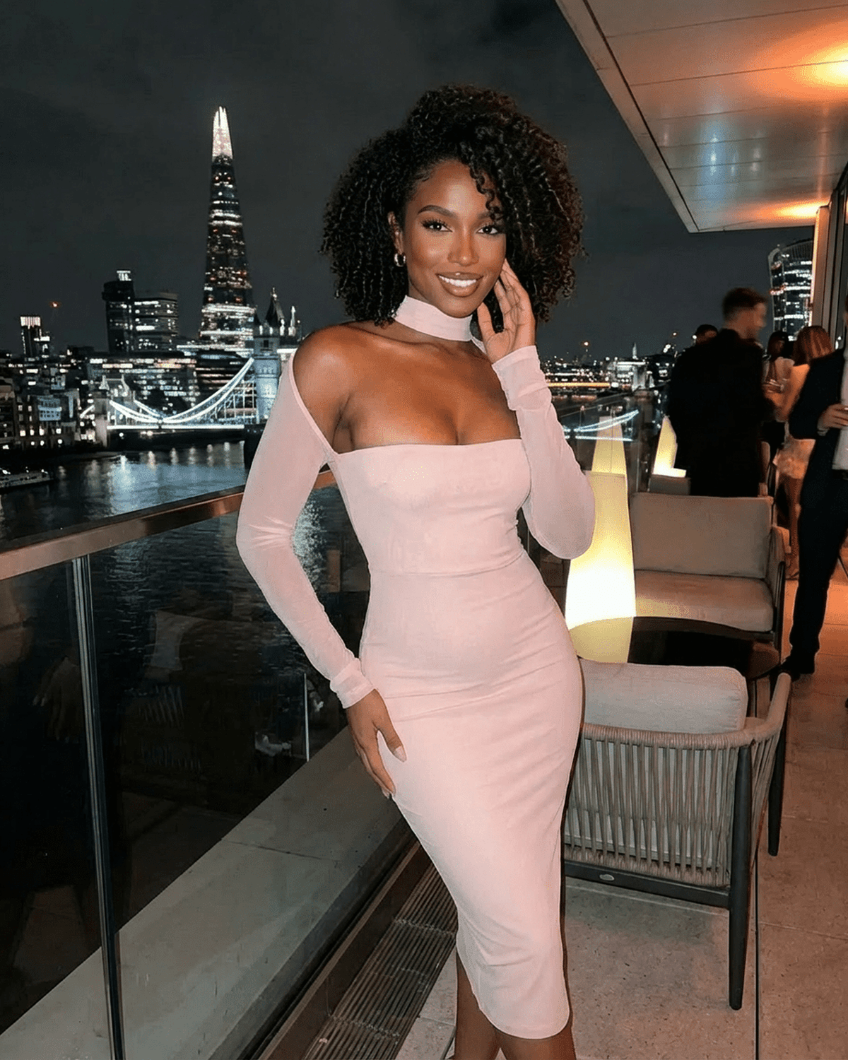 Arden Blush Dress by Lauven worn at night event with city skyline, featuring cutout long sleeves and bodycon fit.