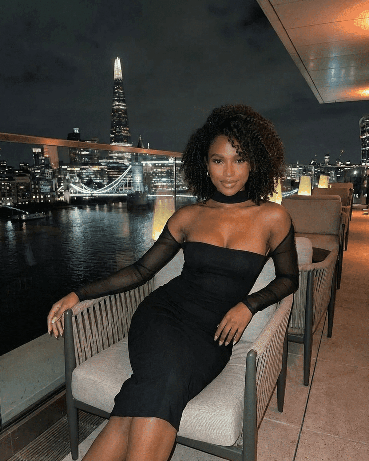 Model wearing the Arden Midi Dress by Lauven, showcasing a sleek silhouette and stylish cutout detail against a city skyline.