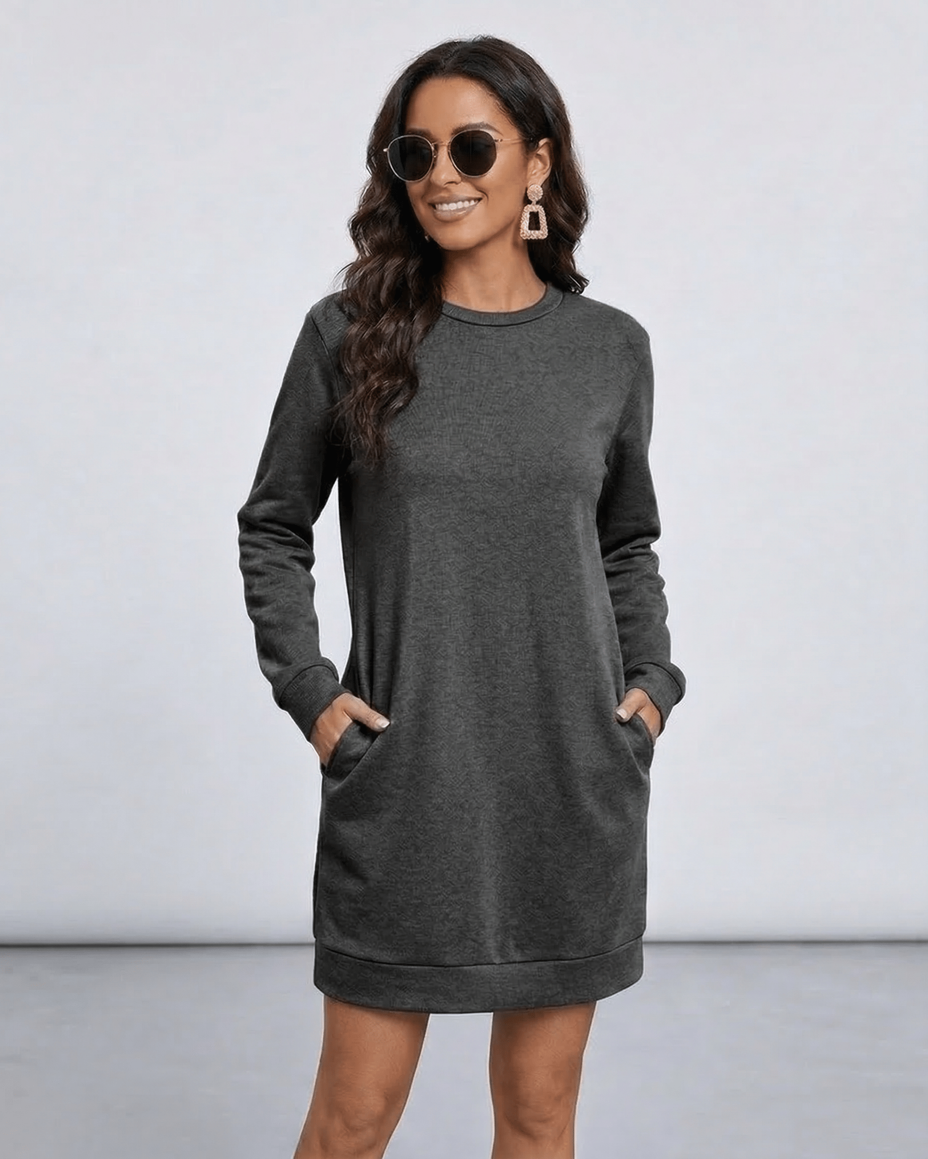 Woman in Astrid Mini Dress by Lauven, a dark charcoal sweatshirt dress with pockets and relaxed silhouette.
