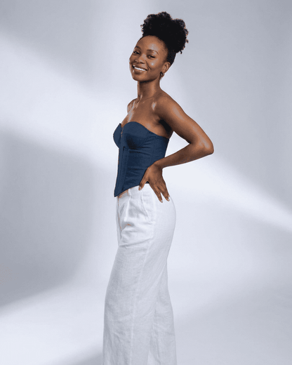 Woman wearing Lauven Atlas Corset Top in faux denim, styled with white wide-leg pants against a light backdrop.