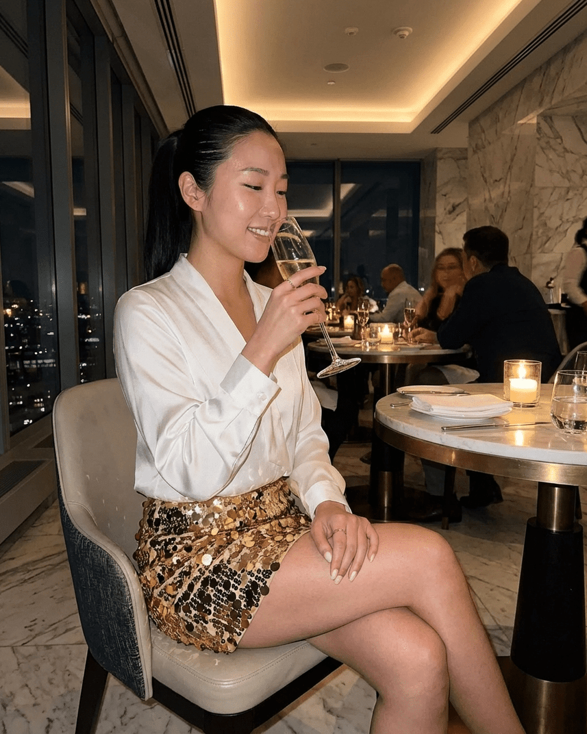 Aurelia Mini Skirt by Lauven, featuring sequins, worn by a woman in a stylish restaurant setting.